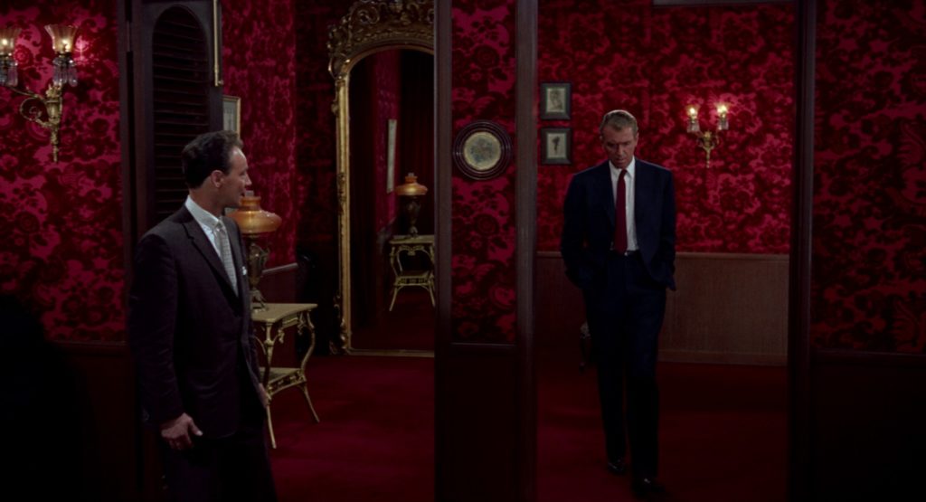 Jimmy Stewart, navy suit and red tie, walking through a red room. Color palettes